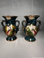 Front view showing both vases with bird motif, teal glaze, gold accents