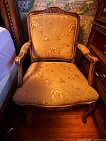 Front view of carved wood armchair showing upholstery and frame details