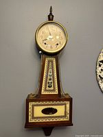Front view of banjo wall clock showing full case, dial, and decorative glass panels