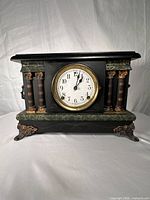 Front view of mantel clock showing dial, columns, marble-style accents, and feet