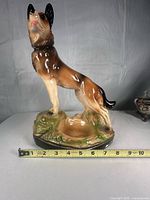Front view of ceramic German Shepherd statue with tape showing base width about 10 inches