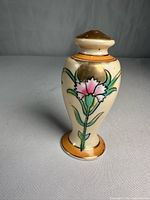 Full view of Nippon porcelain powder shaker showing floral motif and pedestal base
