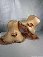 Two peach satin shades with fringe and rosettes