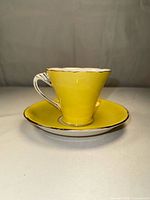 Teacup on saucer front view showing yellow glaze and gold trim