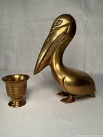 Pelican figurine next to small pedestal vase