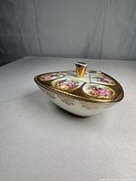 Side view of triangular porcelain dish with gilt knob and courting scenes