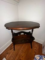 Front angle of wooden end table showing oval top and magazine rack below