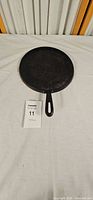 Top view of round cast iron griddle showing overall diameter and handle