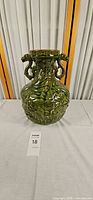 Front view of green ceramic urn showing dragon relief and handles