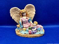 Front view of guardian angel & child resin sculpture showing figures, blocks, teddy bear, wings, colors