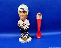 Front view of bobblehead and spoon on blue backdrop