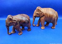 Both wooden elephant carvings side by side on blue backdrop
