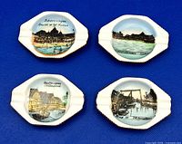 All four ashtrays front view shows size, shape, gilt edging and printed scenes