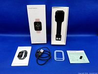 All items laid out: boxed smart watch, watch, cable, bumper, manuals