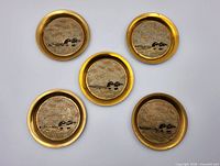 Front view of five brass coasters showing loon enamel design