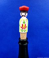 Front view of painted wooden folk art bottle stopper on bottle