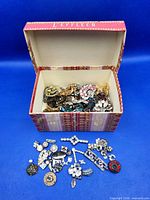 Open L'EFFLEUR box filled with assorted jewelry findings, several pieces displayed in front