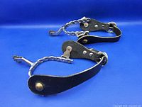 Both spurs showing twisted steel shank, rowels, leather straps and hardware