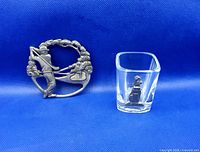 Both items side by side on blue background: pewter golfer jar topper and glass shot glass with pewter golf bag