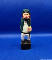 Front view of painted wooden fisherman figure on black base