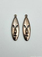 Front view of both mask earrings showing shape and cut-out eyes