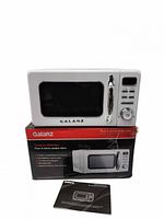 Front view of Galanz microwave on top of its branded box with manual