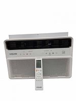 Front view of Vissani window air conditioner with remote placed in front