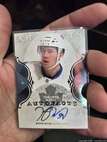Front of Keith Aulie autographed card held in hand showing signature