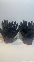 Front view showing four gloves, palm side up, black coating, red cuffs