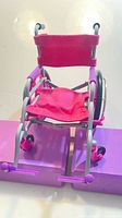 Front view of pink and purple doll wheelchair showing seat and footrests