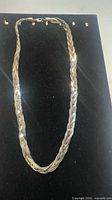 Full view of braided necklace laid flat to show length and clasp