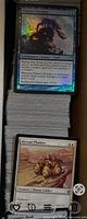 Foil Thassa’s Emissary on stack of sleeveless cards in storage box