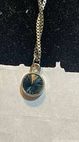 Front view of round blue faceted crystal pendant on silver-tone chain