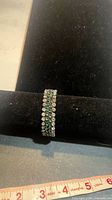 Full bracelet on display bar showing alternating green and clear stones