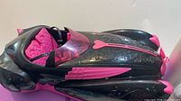 Left side view of black and pink Monster High roadster showing pink seats and hood detailing