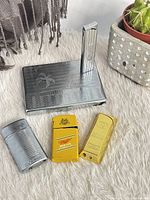 Group shot of cigarette case with built-in lighter and three pocket lighters