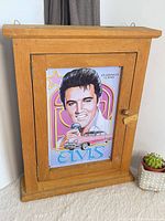 Full view of wooden wall cabinet with Elvis print on door