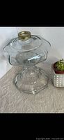 Full view of clear glass kerosene lamp base showing shape and brass collar