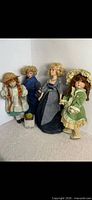 Front view of four porcelain dolls and basket