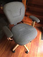 Full view of upholstered swivel chair with wooden arms and base