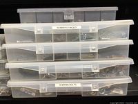 Stacked clear organizer boxes labeled and filled with screws, bolts, nuts