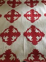 Full view showing overall red appliqué pattern on white quilt