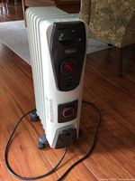Full view of DeLonghi oil-filled radiator heater on casters with power cord visible