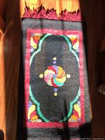 Full view of hooked rug showing design, fringe, size context