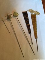 All five hat pins laid out showing relative sizes and styles