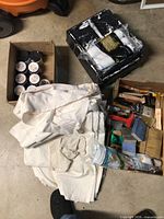 Overview of drop cloths, sample paint cans, brushes, roller covers