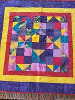 Full view of larger quilt showing geometric multicolour patchwork and border