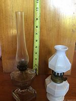 Both oil lamps side by side with measuring tape for scale
