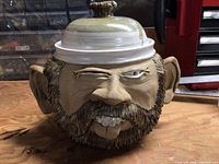 Front view of sculpted face bean pot with lid