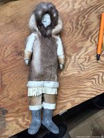Full view of soapstone doll with fur clothing next to pen for scale